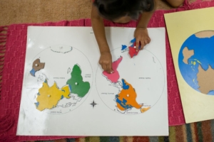Child making a map at Montessori Episcopal School enrollment in Lewisville, TX, demonstrating hands-on learning and exploration of geography.